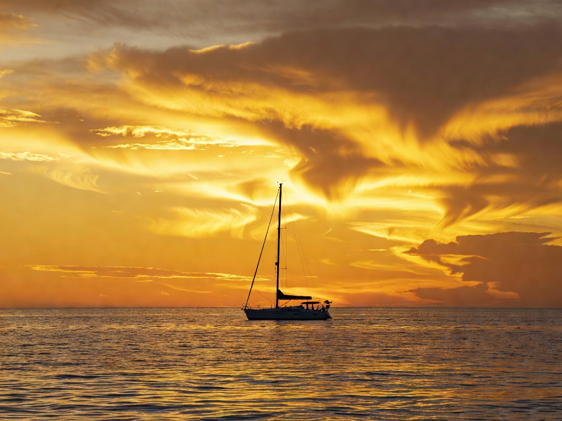 Calm evening view of sailboat mast against orange sunset in Mediterranean